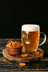 Mug of fresh beer and snack on wooden table