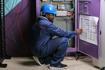 African-American electrician performing wiring in distribution board