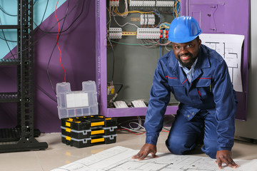 African-American electrician with plan of house indoors
