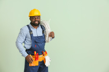 African-American electrician on color background