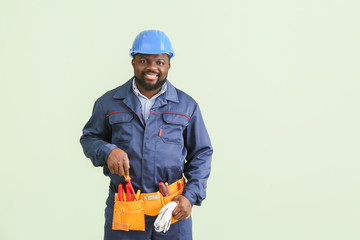 African-American electrician on color background