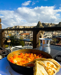 Stewed vegetables in a pan, Turkish pita stand on the table against the background of a blurred background of the city. View from above.