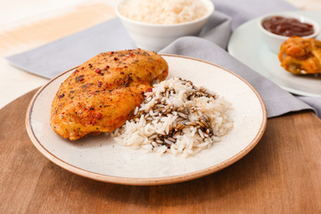 Plate with tasty rice and chicken on table