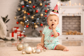 Cute little baby with Christmas balls at home