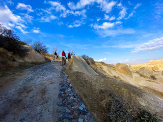 Obraz premium Tourists on horseback go along the road through the mountains. Tourist route. Cappadocia Valley. Turkey. November 5, 2019.