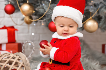 Cute little baby in Santa Claus costume on Christmas eve at home