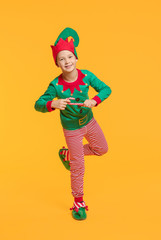 Fototapeta na wymiar Little boy in costume of elf and candy cane on color background