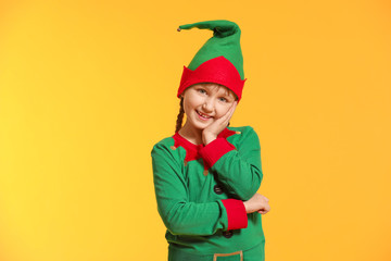 Little girl in costume of elf on color background
