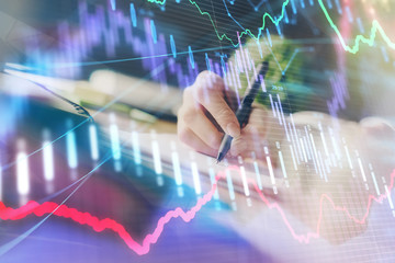 Financial forex graph displayed on hands taking notes background. Concept of research. Multi exposure