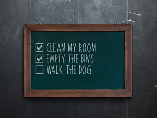 Chalkboard in wooden frame hanging on the wall with a list of chores