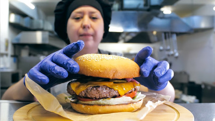Chef making burger. Close-up shot of chef's hands preparing a delicious hamburger with beef rissole...