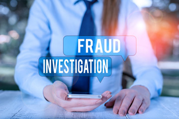 Word writing text Fraud Investigation. Business photo showcasing process of determining whether a scam has taken place Female business person sitting by table and holding mobile phone