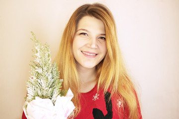 Young girl smiling and holding a small Christmas tree in her hands.