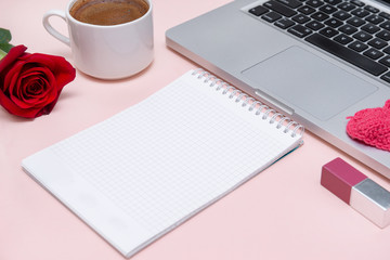 notebook with a clean sheet, a Cup of black coffee, red rose, laptop keyboard, pink lipstick on a beige