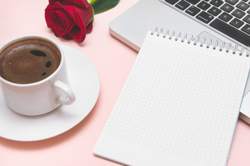 notebook with blank sheet, black coffee Cup, red rose, laptop keyboard