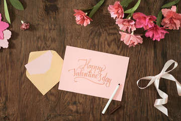 Valentine's day or other holiday concept with card, paper flowers, ribbon on wood background. top view, flat lay, overhead view