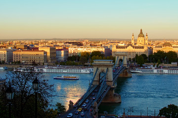 Obraz premium Panoramic autumn view of Budapest. Ancient Chain Bridge over Danube River. Sunset in the city. Medieval buildings along the embankment of the river. Travel and tourism concept. Budapest, Hungary