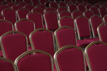 Red empty metal chairs arranged nicely in rows for an event