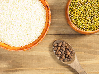 Rice, mung bean, allspice on brown wooden background. Indian cuisine, ayurveda, naturopathy, modern...