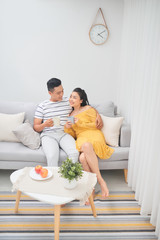 Couple in love enjoying their free time, sitting on a couch,drinking coffee and chatting.