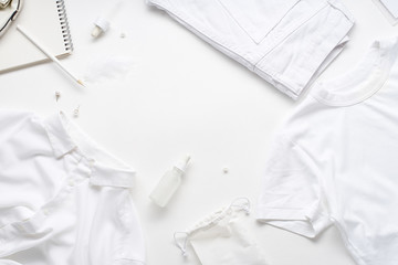 White monochromatic flatlay on white background. Clothes, accessories, stationery and beauty equipment. Blog design concept