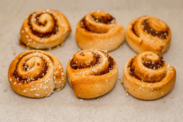 Obraz na płótnie Canvas Freshly baked cinnamon buns rolls on a tray lined with baking parchment paper
