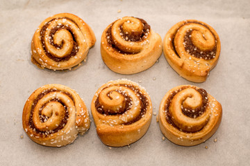 Freshly baked cinnamon buns rolls on a tray lined with baking parchment paper