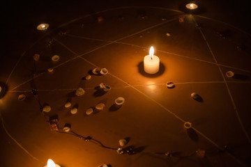 pentagram is painted on the floor, candles are lit, beads are lying, shells are scattered. concept...