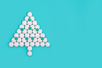 Elegant Christmas tree of white pills on blue background. Christmas and New year concept. Holiday for health care, medical and pharmacy chain. Creative minimalist medicines. Copy space