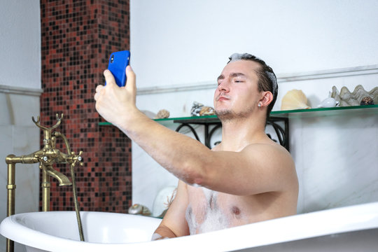 Naked Caucasian Man  Blogger For Social Networks In Bathtub Makes Selfie On Mobile Phone, With Proudly Expression On The Face, Foam Bubbles On The Head And Body. 