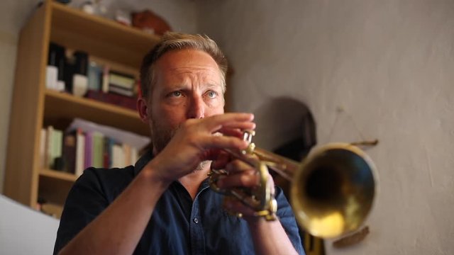 Hombre de mediana edad de pelo rubio tocando la trompeta