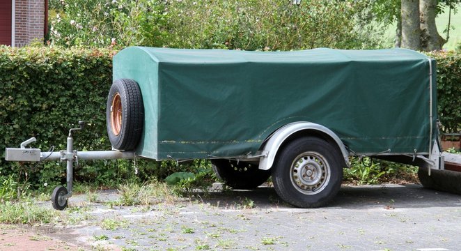 Pkw-Anh&auml;nger mit gr&uuml;ner Plane und Reserverad