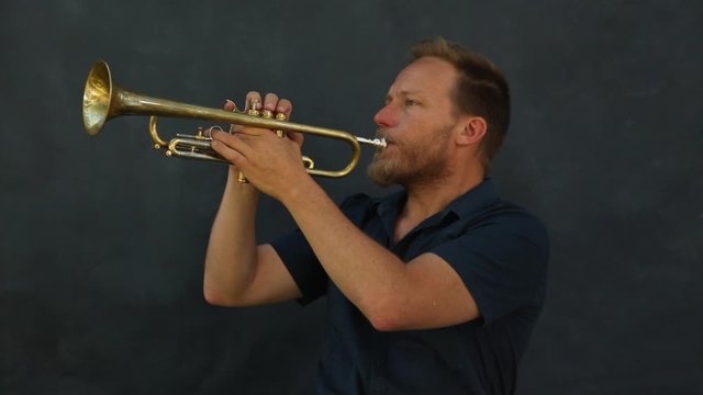 Hombre de mediana edad de pelo rubio tocando la trompeta