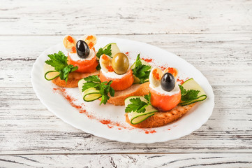 Seafood rolls in a restaurant close-up. Salmon rolls with cheese and olive on toast on a white plate and copy space.