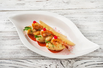 Tiger prawns with red caviar in a restaurant close-up. Fried shrimp on mashed potatoes on a white plate and copy space.
