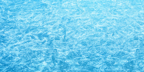 Winter ice rink, panoramic view. Traces of blades of skates on ice, blue winter background