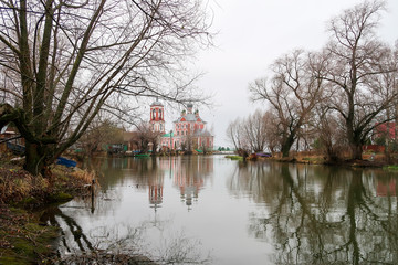 Fototapeta na wymiar Ancient russian church and its reflection in the water surface of the river