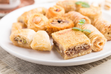 traditional arabic sweets (kunafa, baklava)  and a cup of coffee on a white wooden background. side view, selective focus.