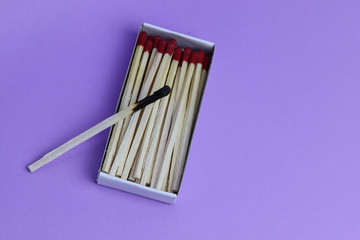 Top view of an open matchbox with one burnt and wholes matches. Burnout. Isolated on a colored background. Loneliness concept.  Copyspace for text.