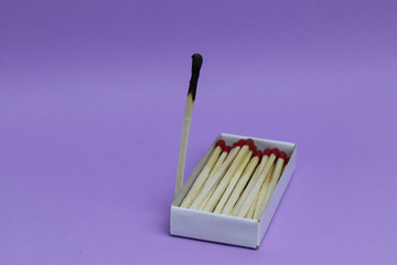 Top view of an open matchbox with one burnt and wholes matches. Burnout. Isolated on a colored background. Loneliness concept.  Copyspace for text.