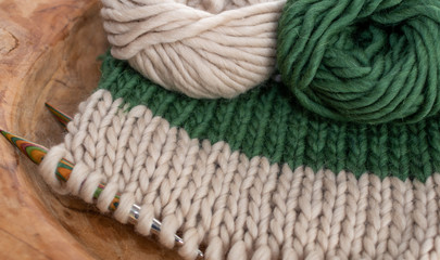 Fototapeta na wymiar beige and green knitting on wooden needles 