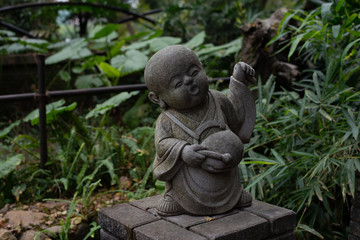 A small statue of a musician in a green garden in China