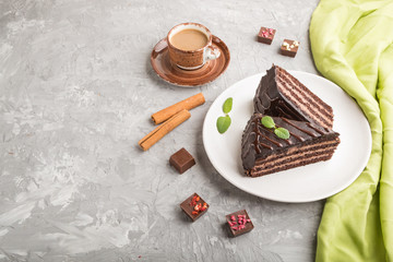Homemade chocolate cake with milk cream and a cup of coffee on a gray concrete background. side view, copy space.