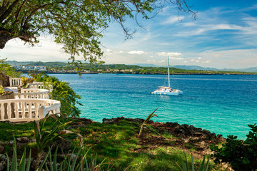 Sailing boat, ocean and coastline view from terrace with white balustrades