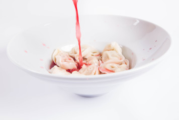 	 Polish Christmas Eve dish:clear borscht with dumplings (uszka) being poured into a plate	