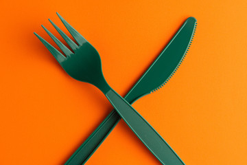 Plastic Fork And Knife On Orange Background, Green Plastic Fork And Knife