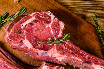 Raw ribeye steak, spices and rosemary on cutting board. Top view