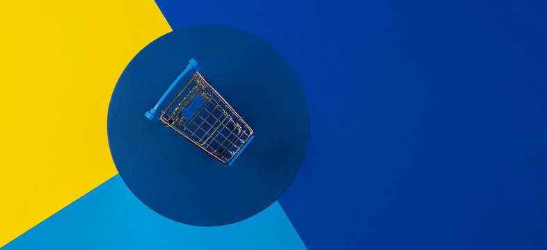 Mini shopping trolley cart on red yellow navy blue background. Online shopping, buy, sale, discount concept