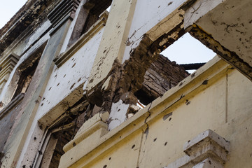 Destroyed building after hostilities. Photo of the destroyed building, the theme of the war. Military actions. Wall with holes in several places. Crumbling wall of hostilities.