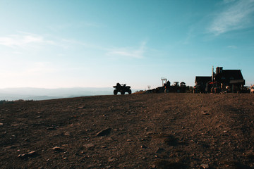Fototapeta premium ATV in the nature. A beautiful sunny landscape with mountains. Blue sky, grass and forest. Background or wallpaper.